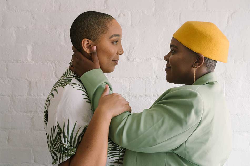 Two people with short hair embrace