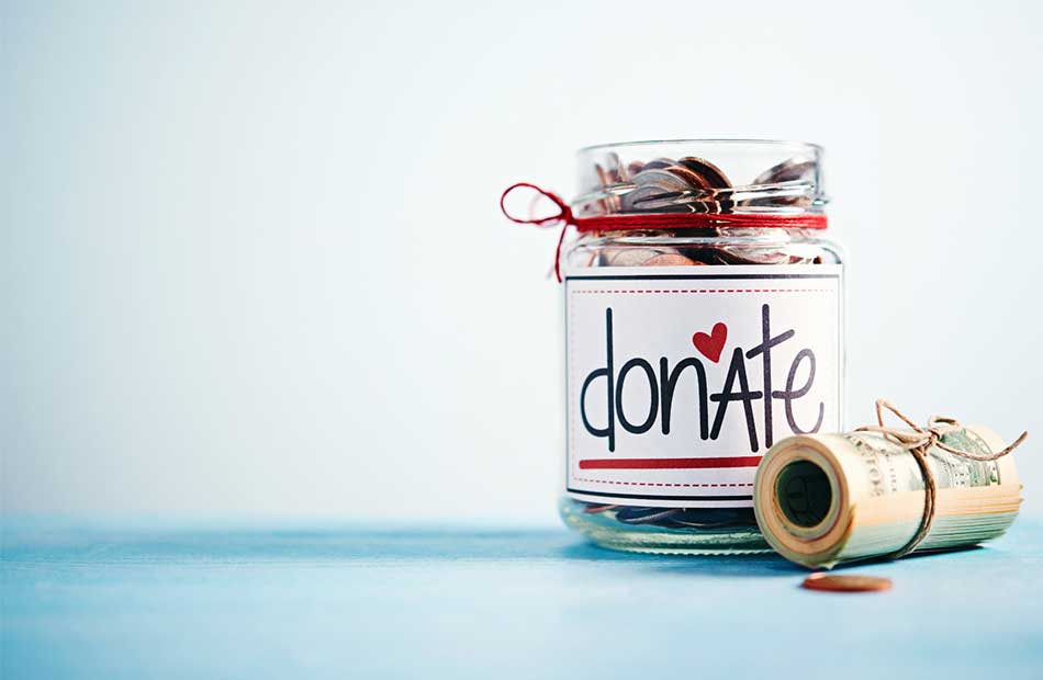 Image of a jar with coins in it labeled "donate" and a roll of dollar bills placed next to it.