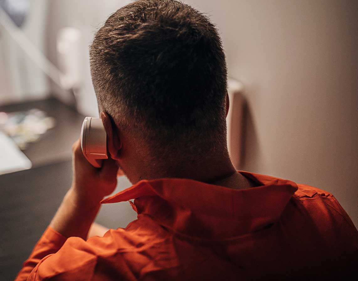 Picture of an incarcerated man on call on a payphone.