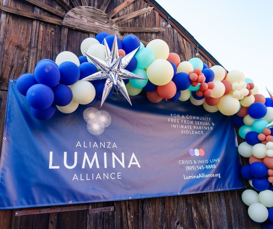 Pancarta de Alianza Lumina rodeada de globos en el evento de lanzamiento de la marca